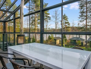 Ein Wintergarten mit Glasdach, einem weißen Tisch und Stühlen.