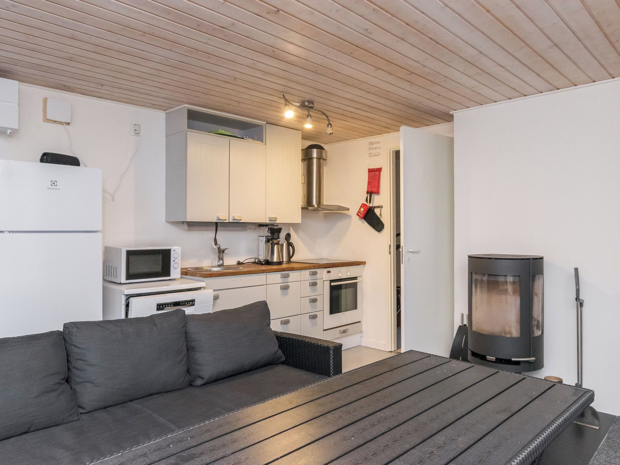 A compact kitchen with a microwave, stove, and kettle.
