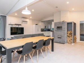 Una cocina moderna con horno empotrado, un comedor con mesa y sillas de madera, y una chimenea de piedra.