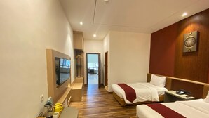 A hotel room with two beds, a TV, a desk with a tray, and a wooden floor. - Parkside Meuligoe Hotel (Meulaboh)