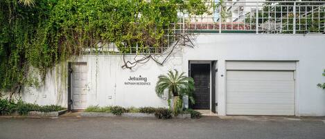 Un edificio residencial llamado Jetwing con fachada blanca, una puerta negra y una puerta de garaje cerrada.