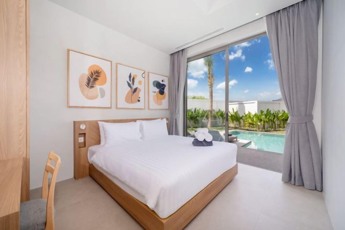 Habitación de hotel moderna con una cama grande, vista a una piscina y obras de arte en la pared.
