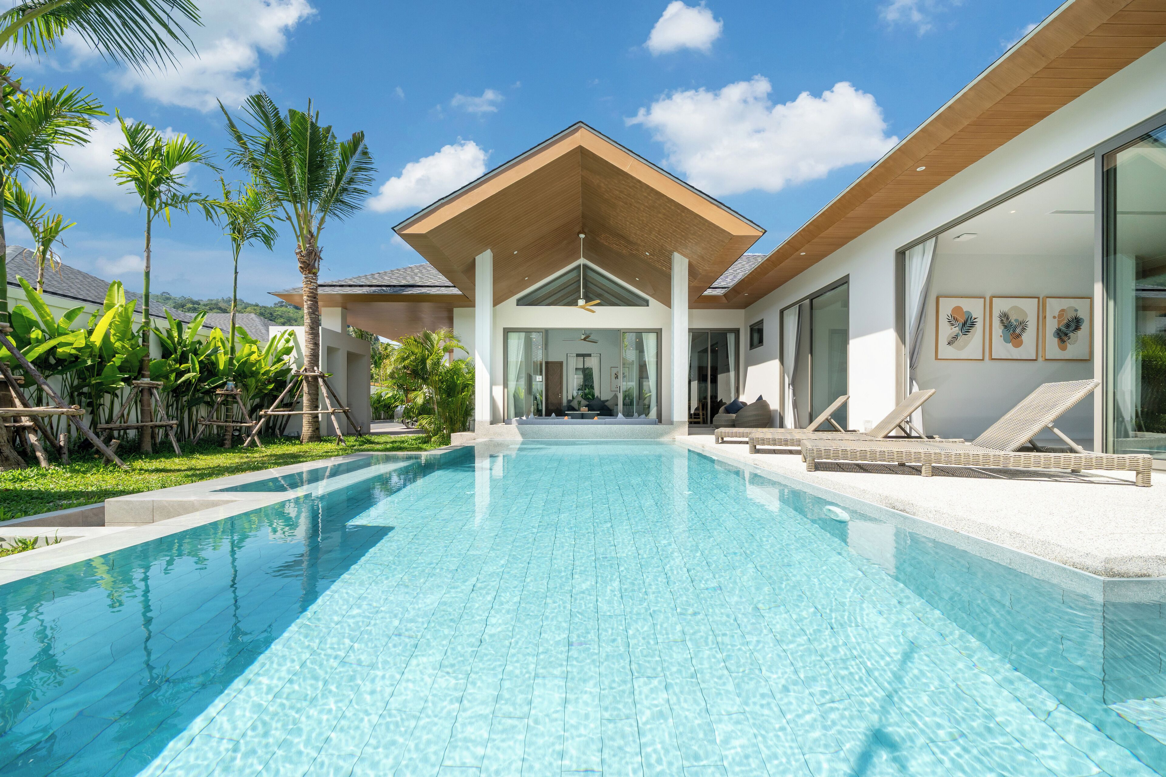 A modern resort with a swimming pool, palm trees, and a large building with a sloped roof.