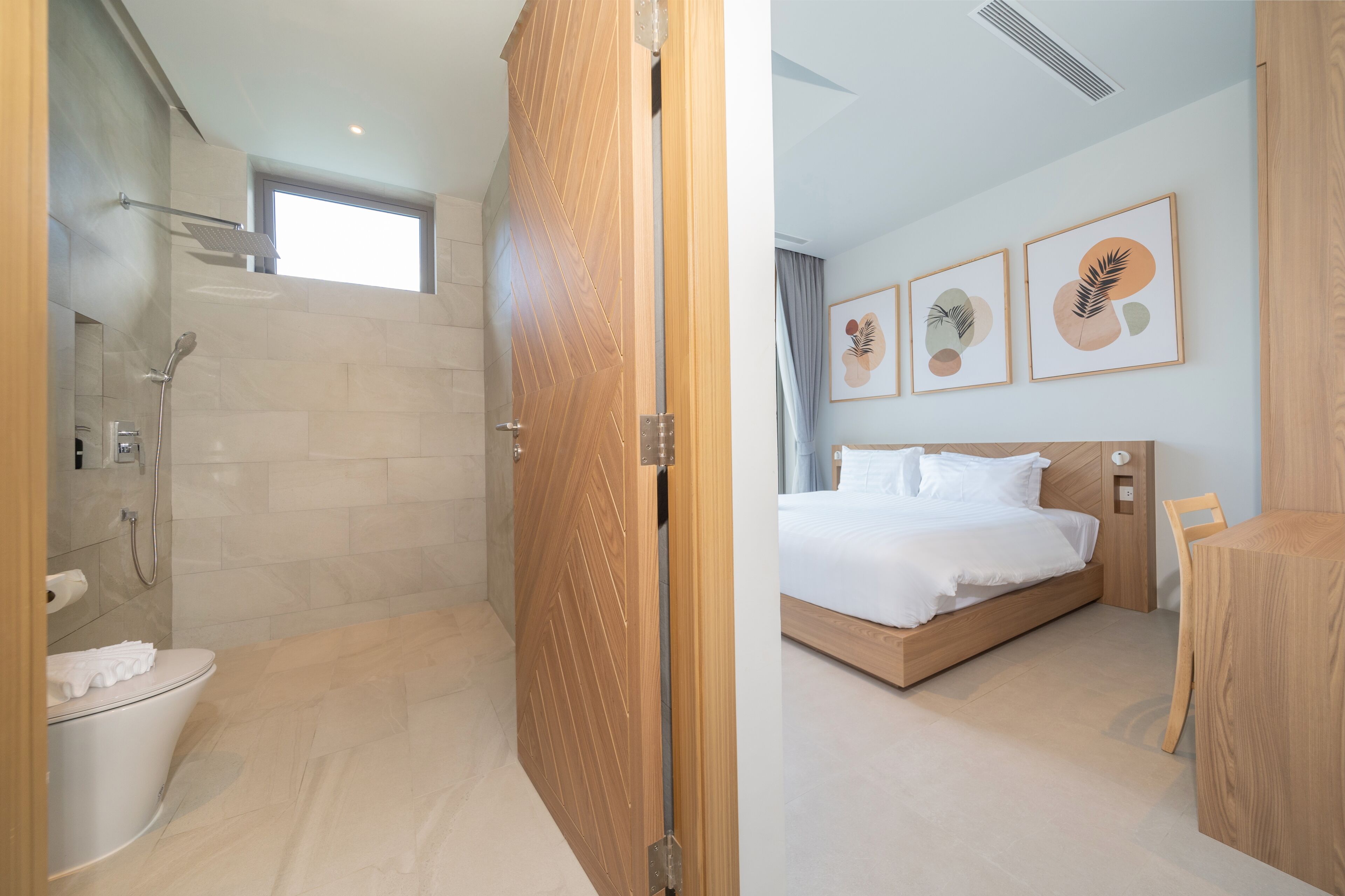 A modern hotel room with a shower, toilet, bed, and a wooden desk.