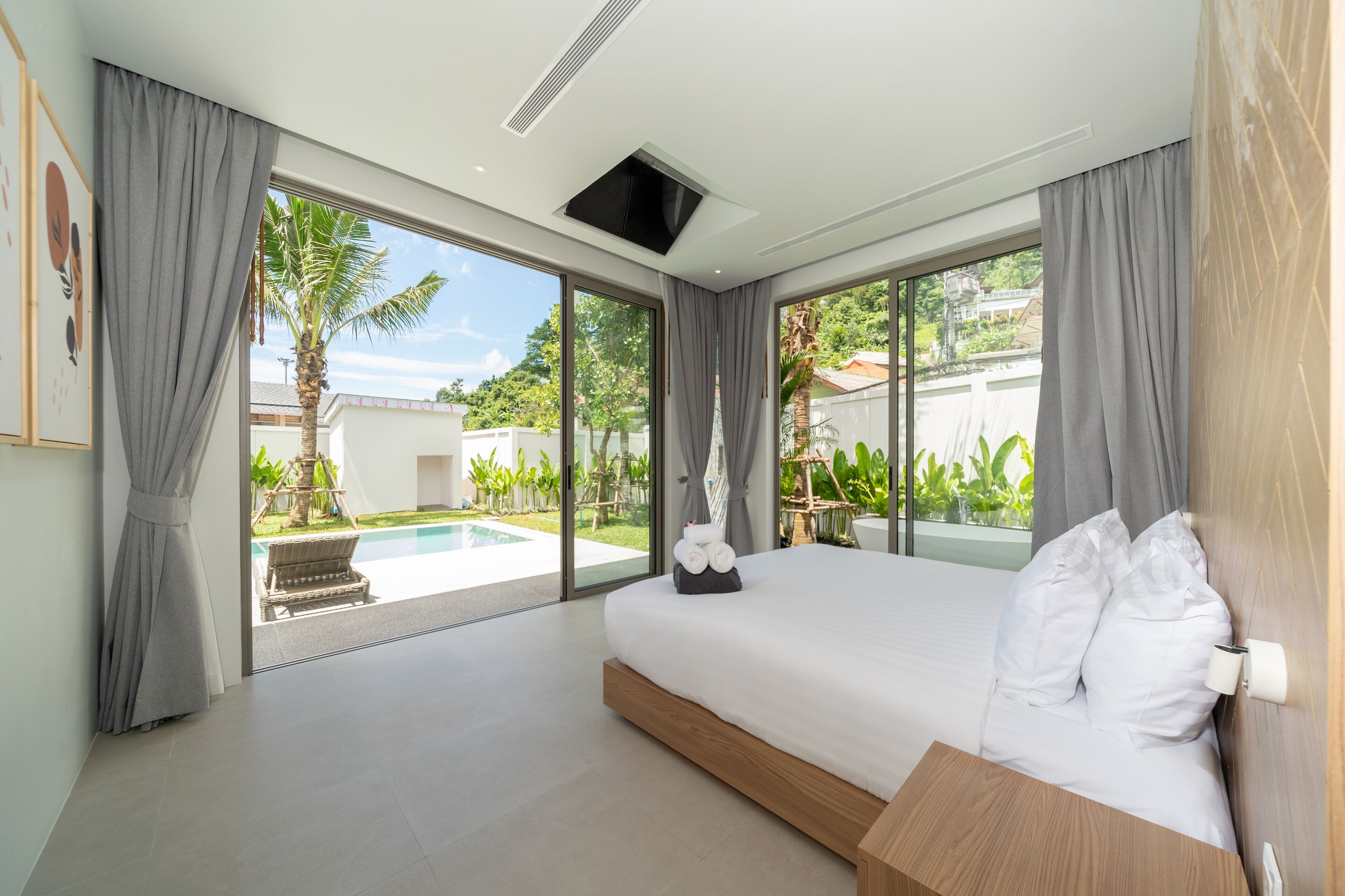 Una camera da letto moderna con un letto grande, vista su una piscina e un balcone con piante.