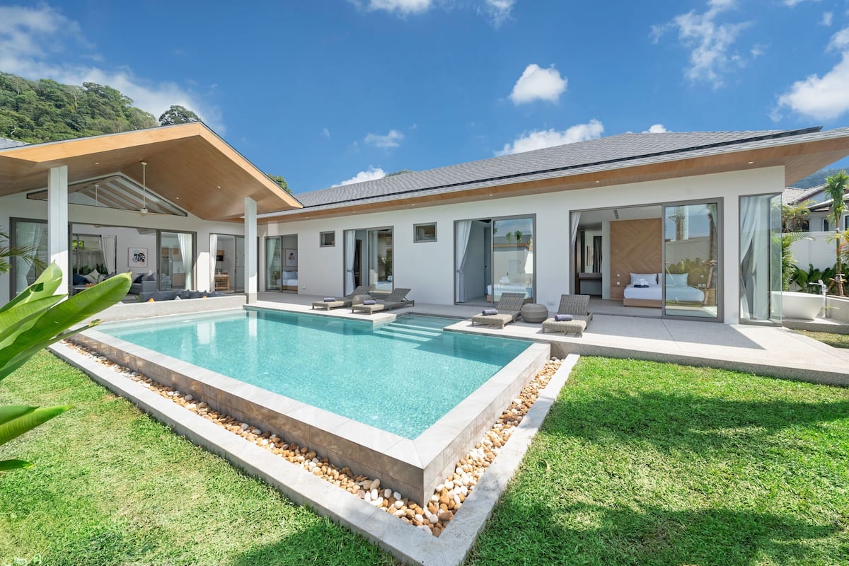 Una casa moderna amb piscina, mobiliari exterior i vistes a la vegetació circumdant.
