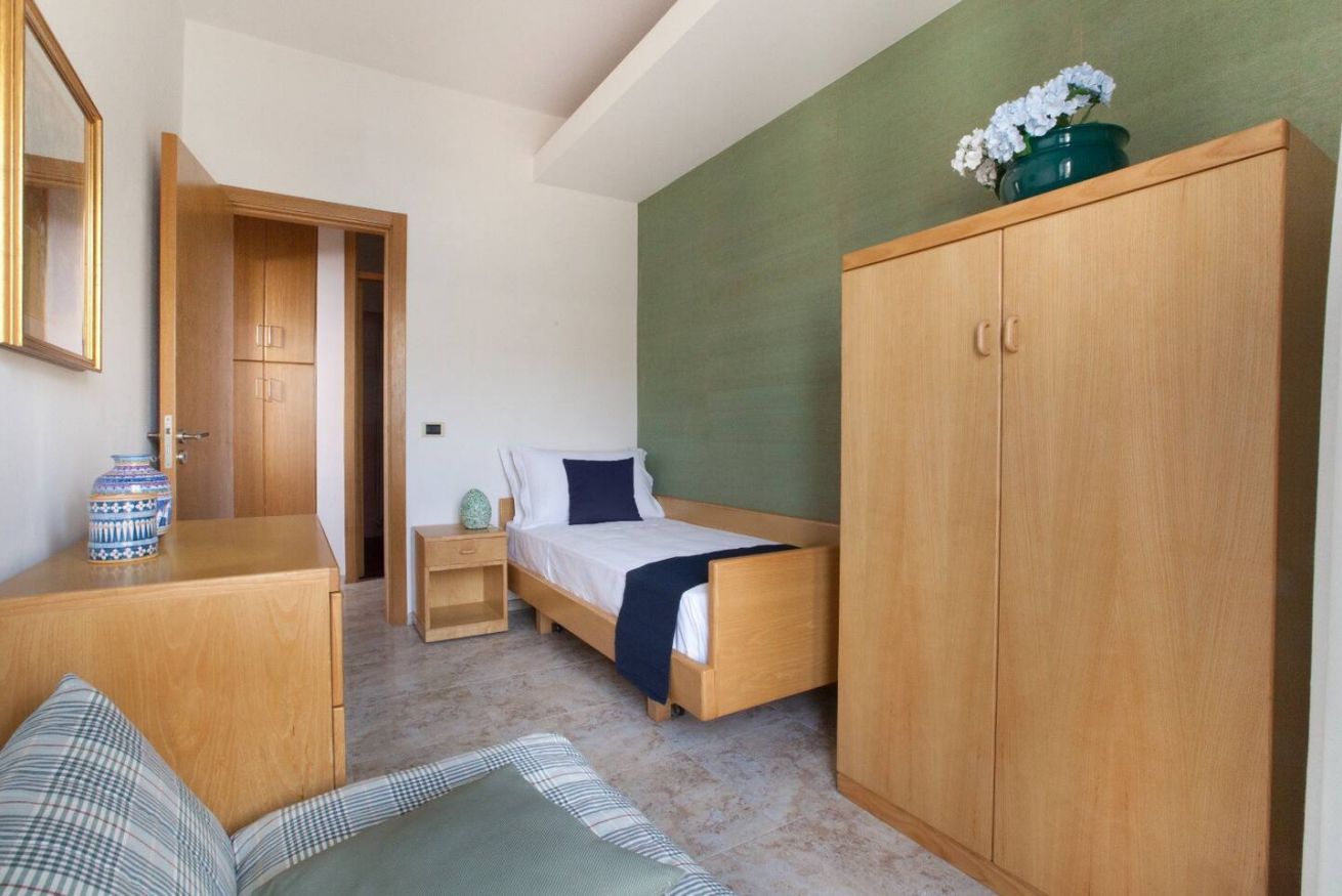 A bedroom with a wooden bed, a wardrobe, a bedside table, and a mirror.