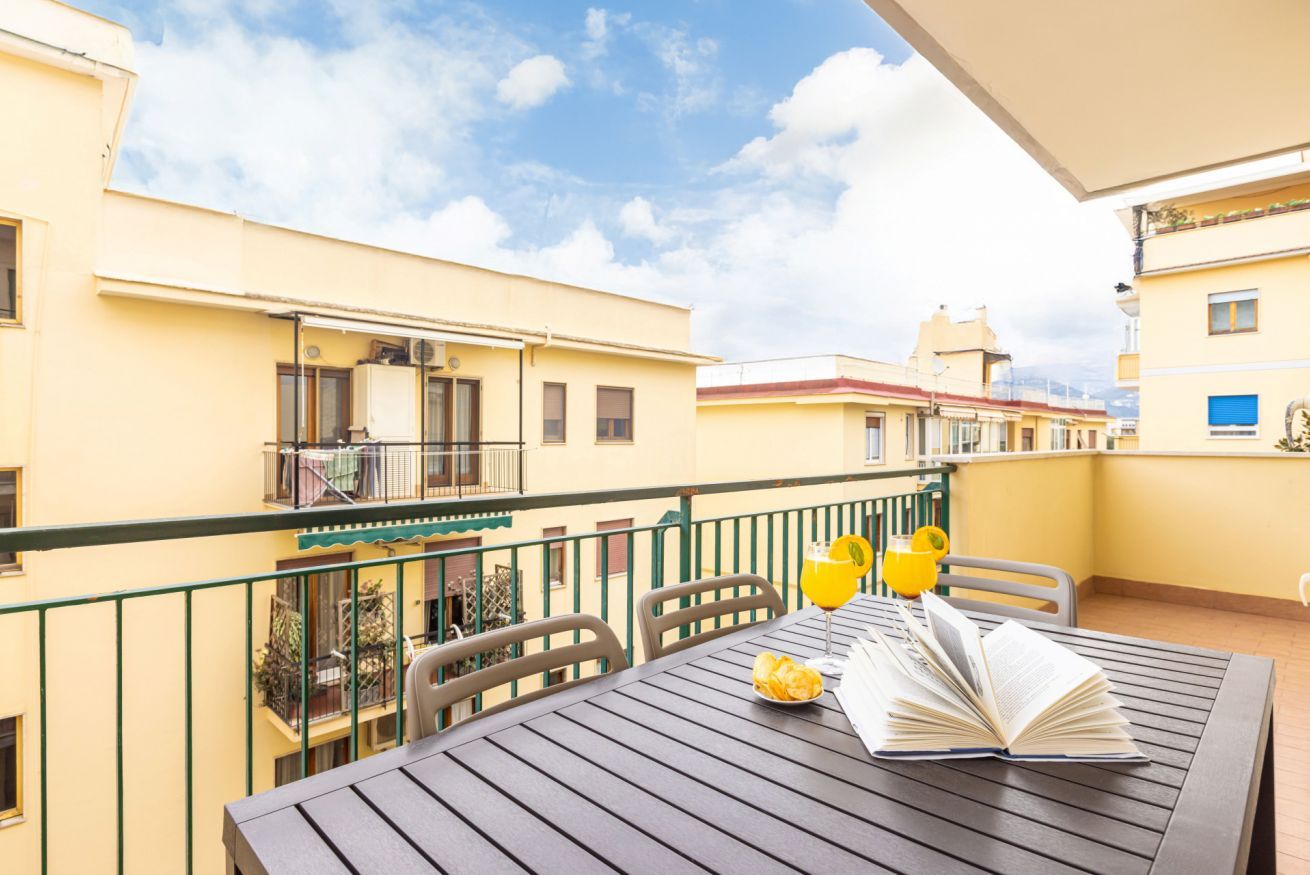 A balcony with a table, chairs, and a book.