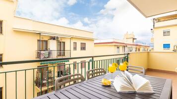 A balcony with a table, chairs, and a book.