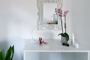 A white vanity with a mirror, a potted orchid, a makeup organizer, and a bottle of lotion. - Sea view Rooftop Apartment with Jacuzzi & Garden (Sorrento)