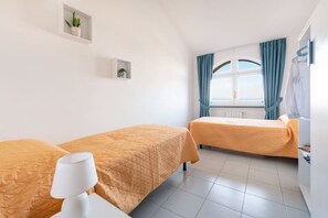 A room with two beds, a white lamp, a window with curtains, and a radiator. - Sea view Rooftop Apartment with Jacuzzi & Garden (Sorrento)