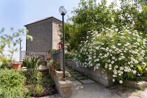 Un bâtiment doté d’une façade en pierre, d’une porte rouge et d’un escalier menant à un balcon.