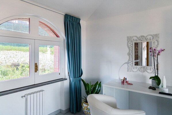 Une salle de bain avec une baignoire blanche, un lavabo blanc, un miroir doté d’un cadre orné et une fenêtre avec un rideau.
