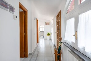 A hallway with wooden doors, a radiator, and a window with curtains. - Sea view Rooftop Apartment with Jacuzzi & Garden (Sorrento)