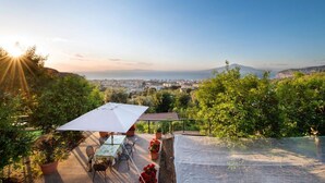 An outdoor terrace with a table and chairs, surrounded by potted plants and a view of a cityscape. - Sea view Rooftop Apartment with Jacuzzi & Garden (Sorrento)
