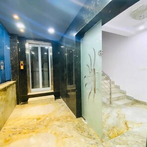 A marble-floored hallway with a glass door and a staircase leading to an upper level. - Hotel Kp Suites Grand (Hyderabad)