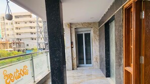 Un balcón con suelo de mármol, puerta de madera y puerta de ascensor de vidrio.