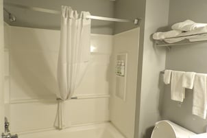A bathroom with a shower curtain, a towel rack with towels, and a toilet.