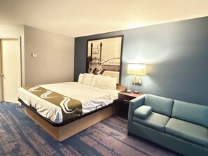 A hotel room with a bed, a nightstand, a lamp, and a sofa. - Northwood Inn Prairie Du Chien (Prairie Du Chien)