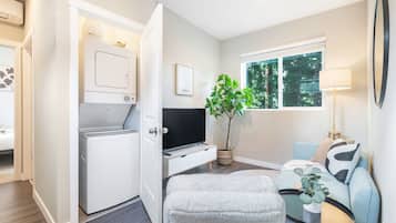 A compact living space with a laundry area, a sofa, a coffee table, and a potted plant.
