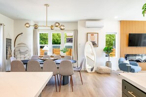 A modern living room with a TV, seating, and a dining area with a table and chairs. - AC · Walks to Cap Hill · Parking · Newly Renovated (Seattle)