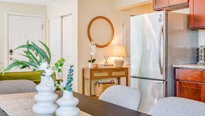 A modern kitchen with a refrigerator, wooden cabinets, and a dining area with a table and chairs.