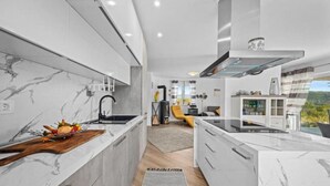 Een moderne keuken met marmeren aanrechtbladen, een centraal kookeiland en uitzicht op de omgeving.