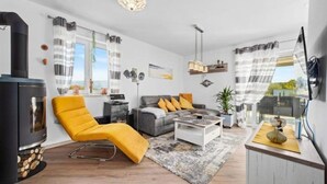 Een moderne woonkamer met een bank, fauteuil en een open haard.