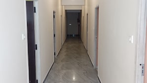 Un pasillo con suelo de mármol, paredes blancas y puertas a ambos lados.