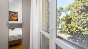Une chambre à coucher comprenant un lit, une armoire et une fenêtre donnant sur des arbres et un parc.