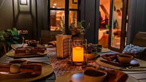 A dining table set with wooden bowls, plates, and a candle.