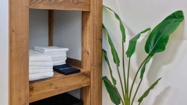 A wooden shelf with neatly folded white towels and a black item. - Lakefront•Sauna•Private Dock•Kayaks•Hot Tub•Fire Pit (Mill Spring)