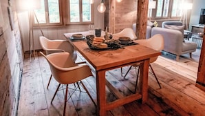 Een rustieke houten eethoek met een tafel voor twee personen, omringd door witte stoelen.