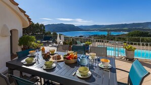 Une table à manger dressée avec des aliments pour le petit-déjeuner, donnant sur une piscine et des montagnes.