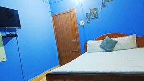 A bedroom with a wooden bed, a television mounted on the wall, and a door.