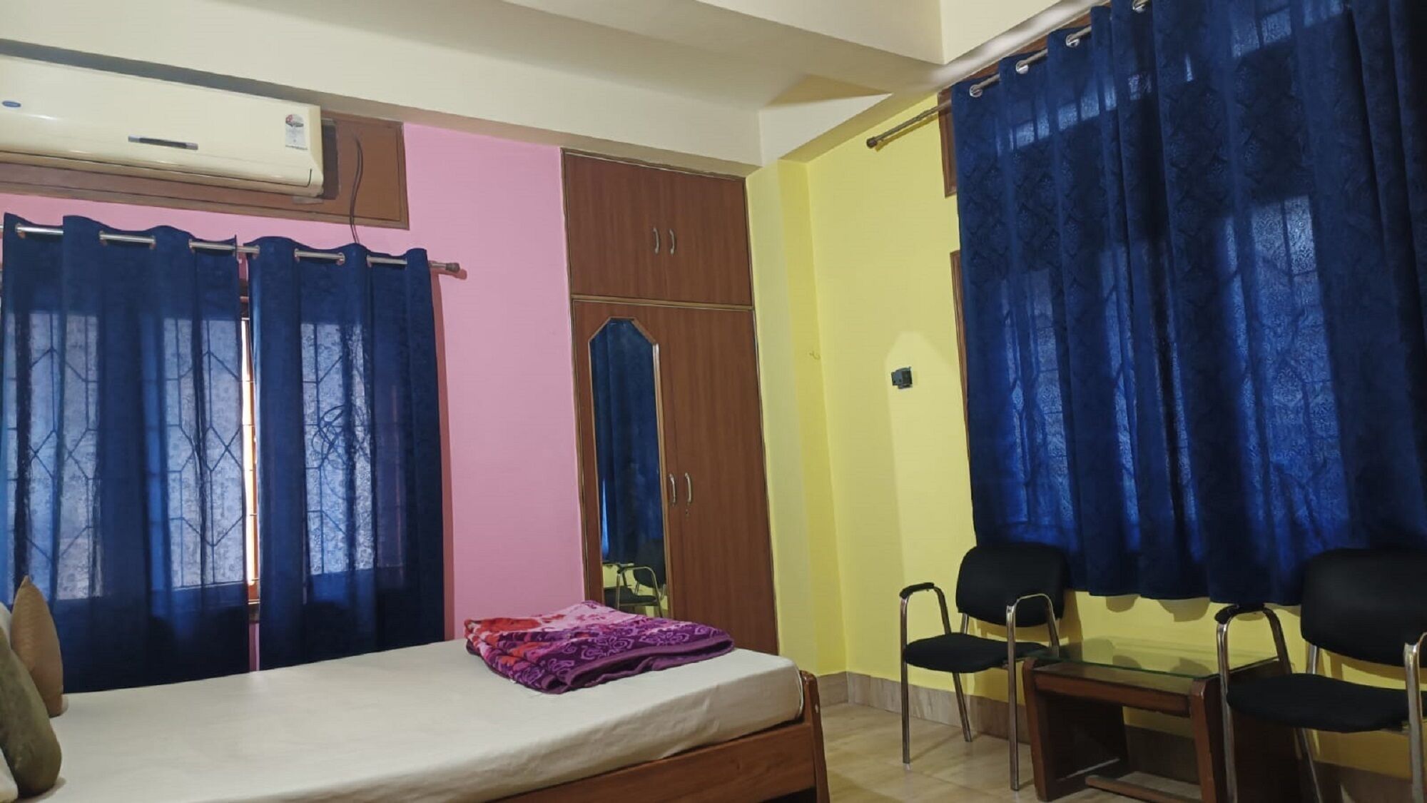 Un dormitorio con una cama, un armario, un escritorio y dos sillas.