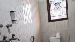 A small, tiled bathroom with a toilet, a shower, and a window.