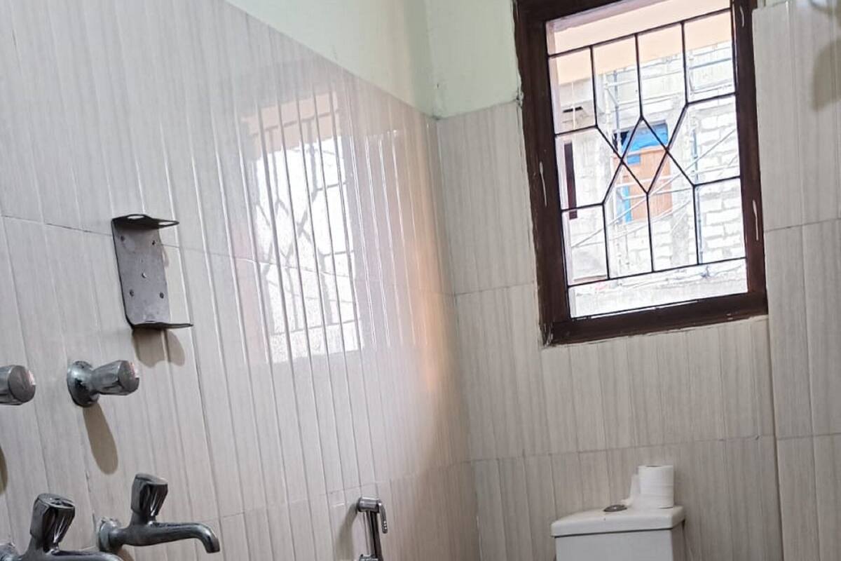 A small, tiled bathroom with a toilet, a shower, and a window.