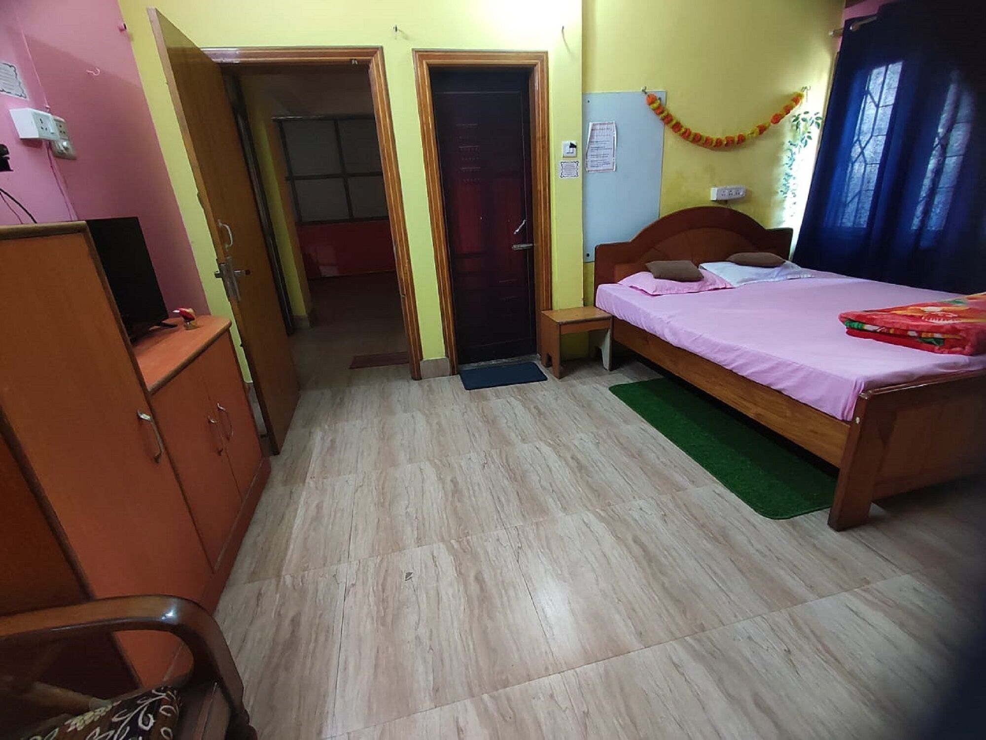A bedroom with a bed, a wardrobe, a desk, and a door leading to another room.