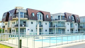 Un hôtel moderne à plusieurs étages, doté d’une piscine, de balcons et d’une façade en verre.