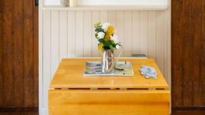 A room with wooden doors, a wooden table with a vase of flowers, and framed pictures on the wall. - Host Stay Tide Time (Great Yarmouth)