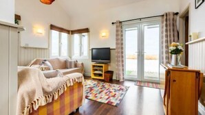 A cozy living room with a sofa, a television, and a patterned rug. - Host Stay Tide Time (Great Yarmouth)