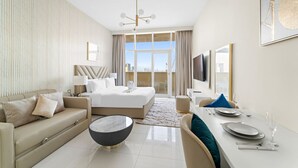 Ein modernes Hotelzimmer mit Bett, Sofa, Esstisch für zwei Personen und einem großen Fenster mit Blick auf die Stadt.