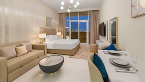Ein modernes Hotelzimmer mit Bett, Sofa, Esstisch und einem großen Fenster mit Blick auf die Stadt.