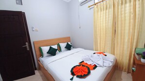 Un letto rifatto con cura, con cuscini bianchi e verdi, una testiera in legno e una tenda gialla.