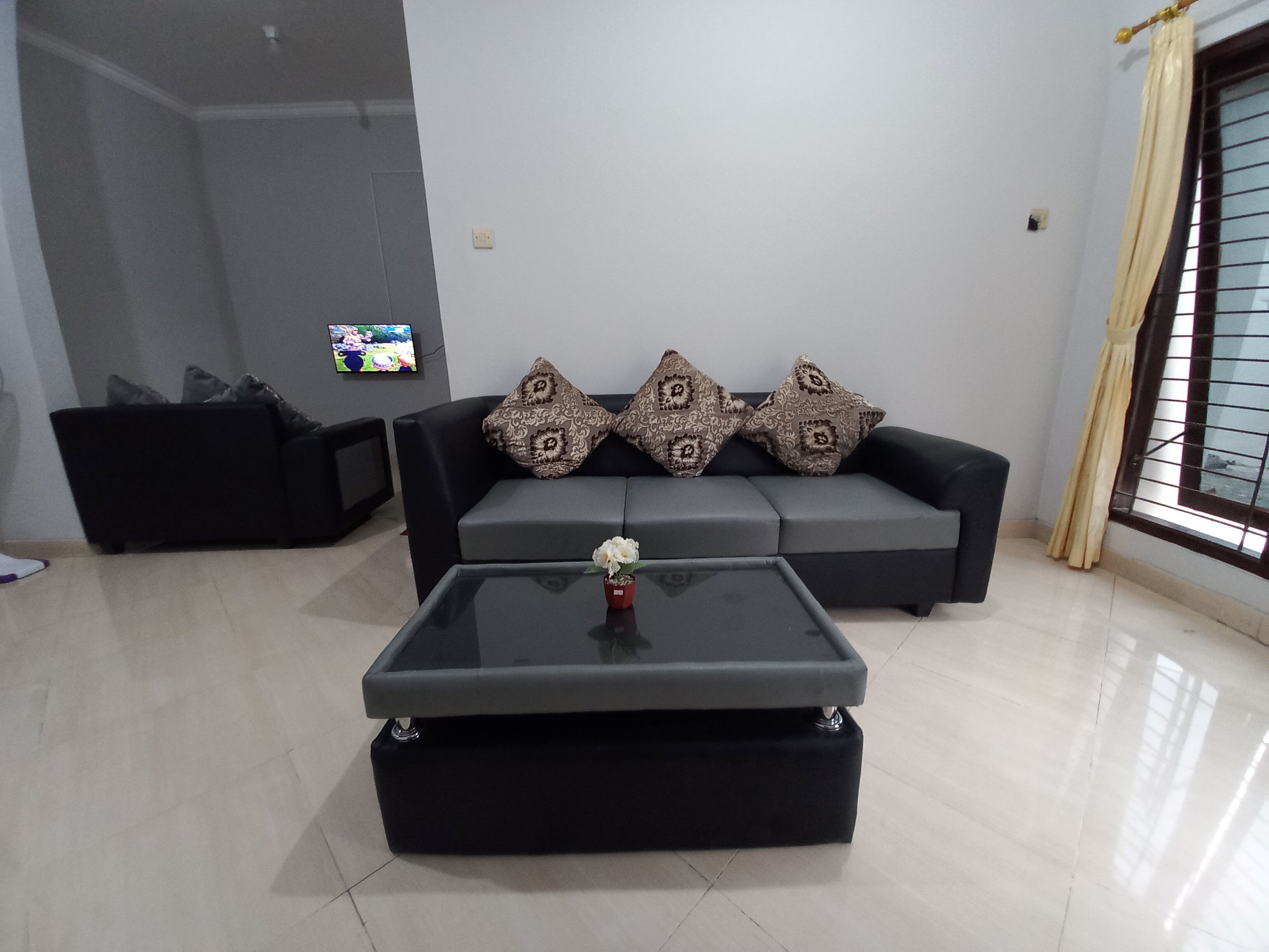 A modern living room with a grey sofa, a black coffee table, and patterned cushions.