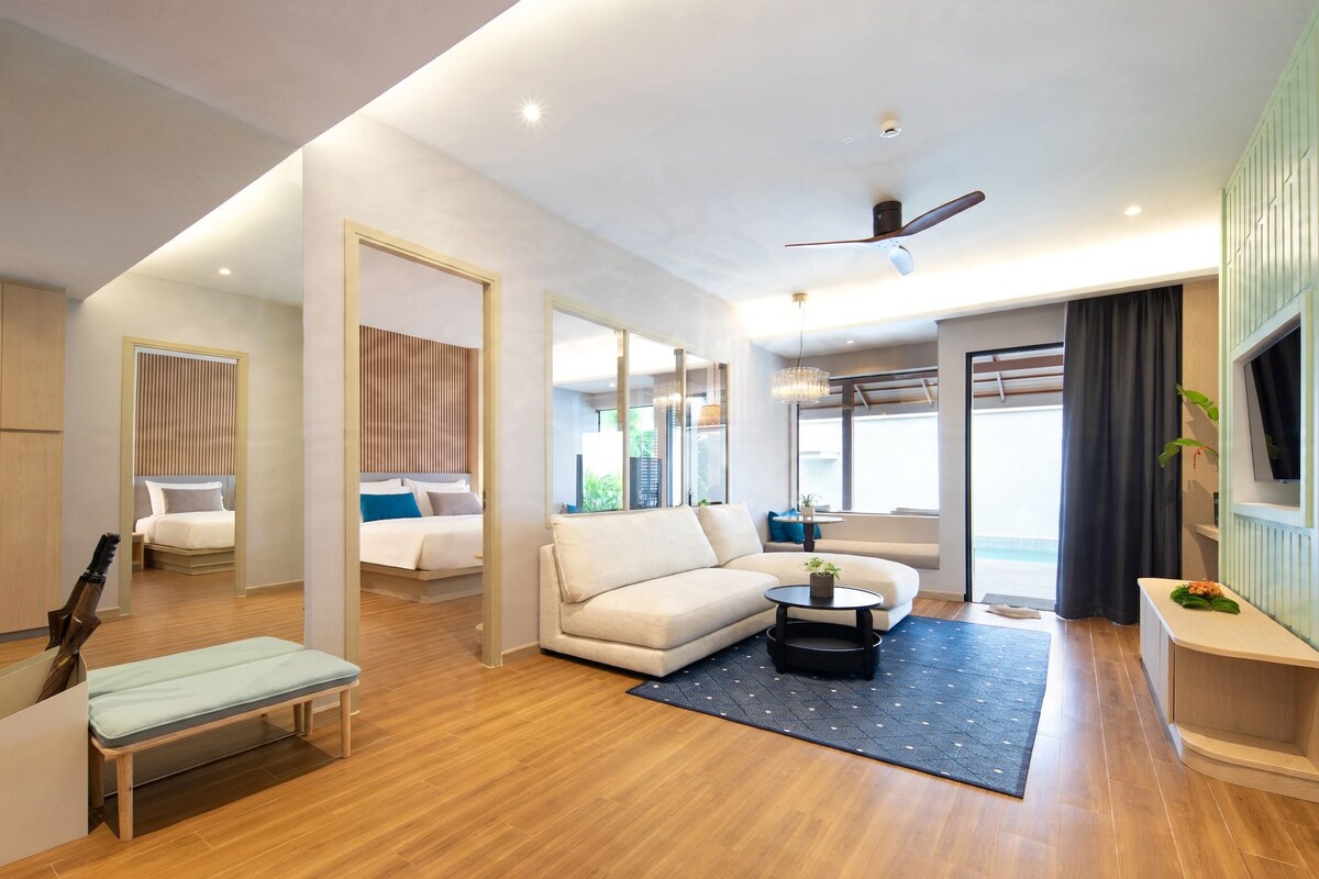 A modern hotel room with a bed, sofa, and a dining area.