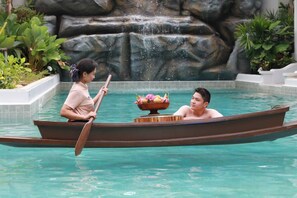 A boat with two people in a pool, a waterfall in the background, and a stone wall. - Lalynn Resort & Villas, Phuket (Thep Krasattri)