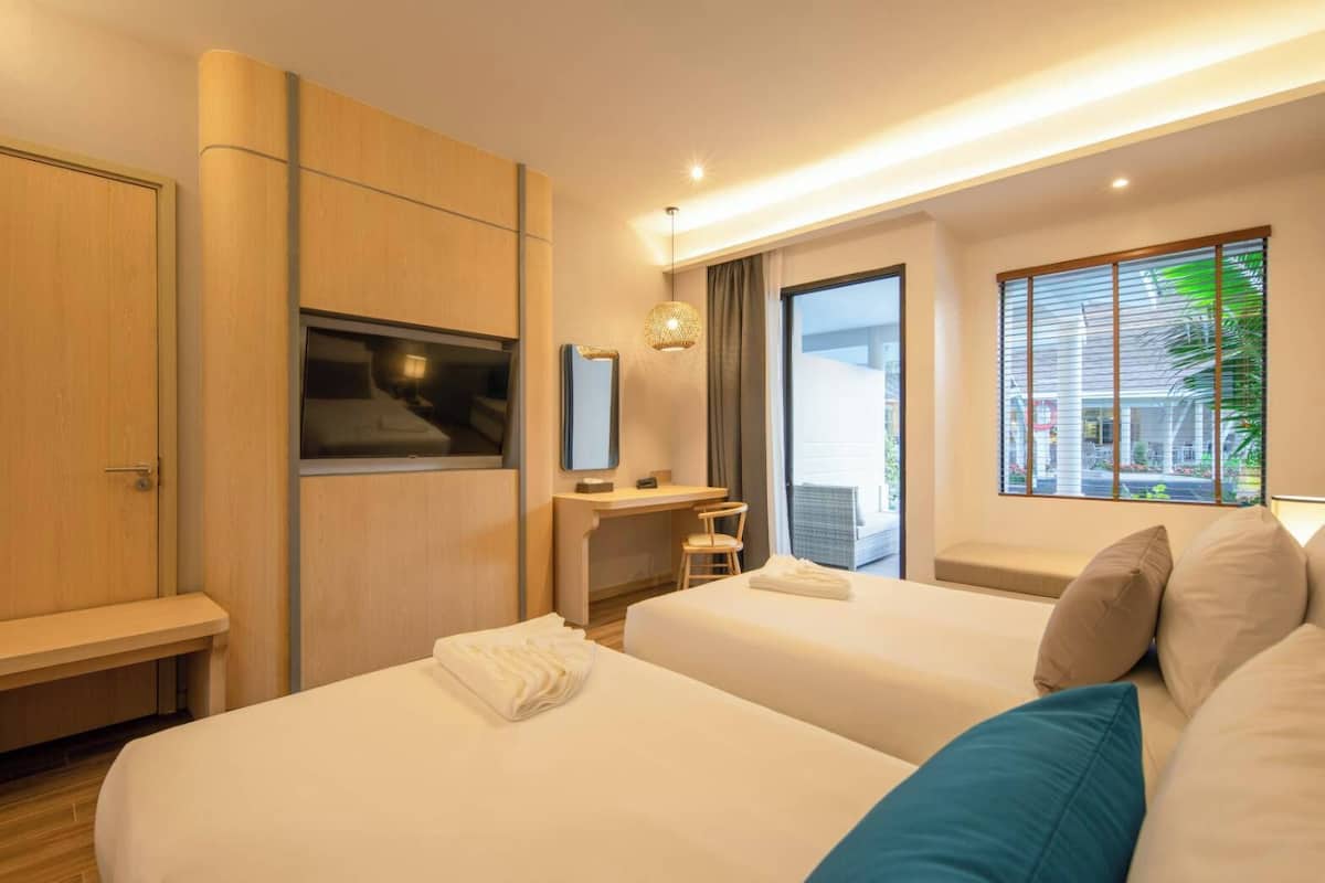 Een moderne hotelkamer met twee bedden, een bureau, een stoel en een groot raam met uitzicht.