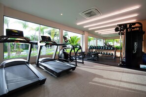 Une salle de sport équipée de tapis de course, d’haltères et d’autres appareils d’exercice.